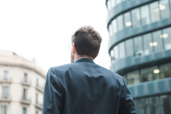 rear-view-businessman-looking-corporate-building-city